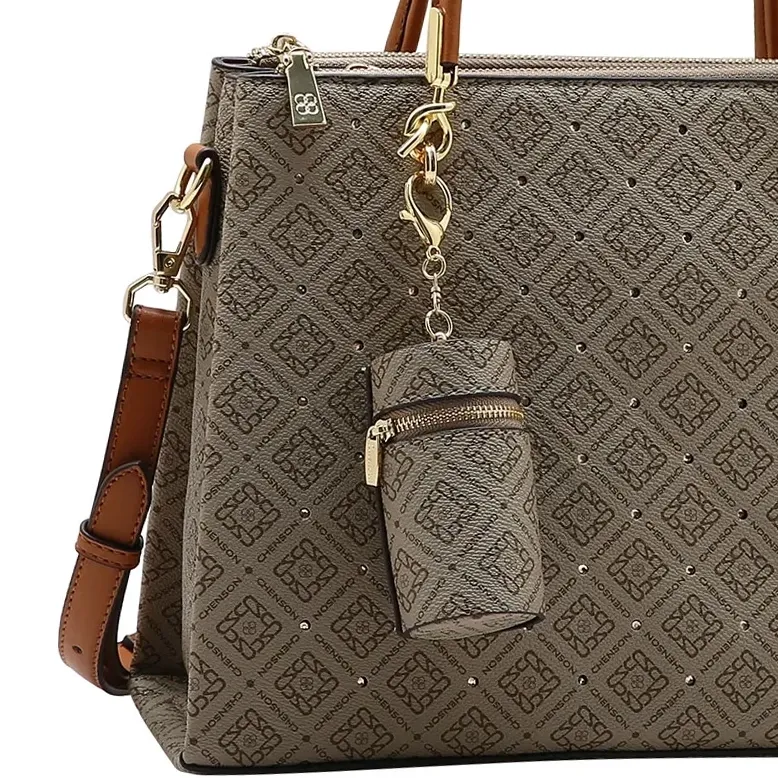 Detalhe da bolsa tote Chenson bege mostrando pingente mini bolsa e fecho dourado